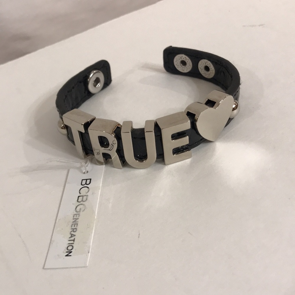BCBGeneration bracelet. Black w/ silver charms & 2 snap fasteners. New w/ tag.